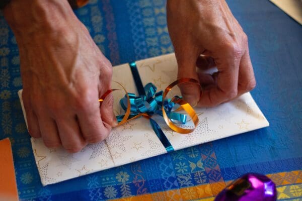 A person preparing a card with blue and gold ribbons