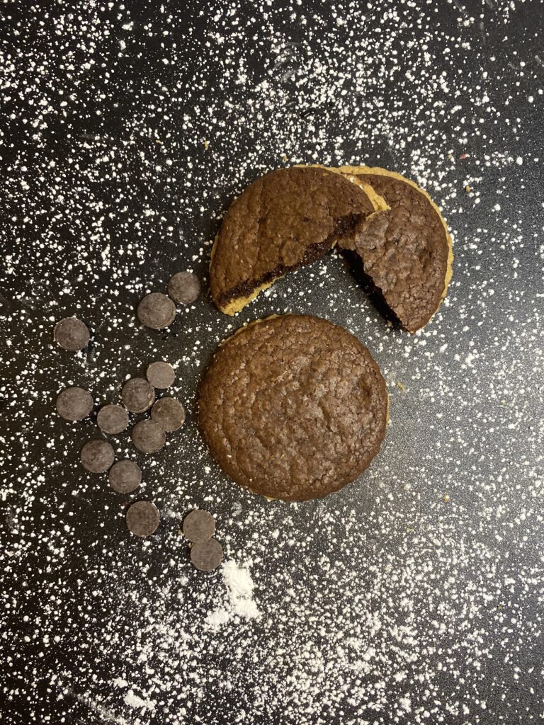 Two pieces of cookies beside some chocolate chips