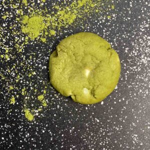 A green cookie dough on a black surface