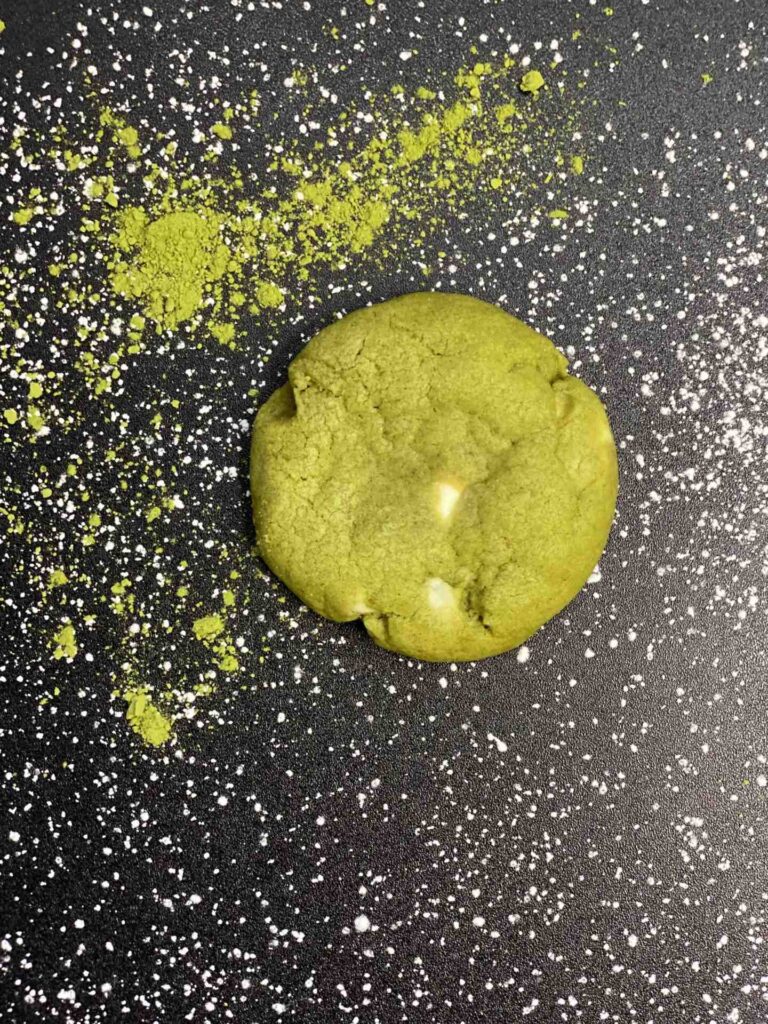 A green cookie dough on a black surface