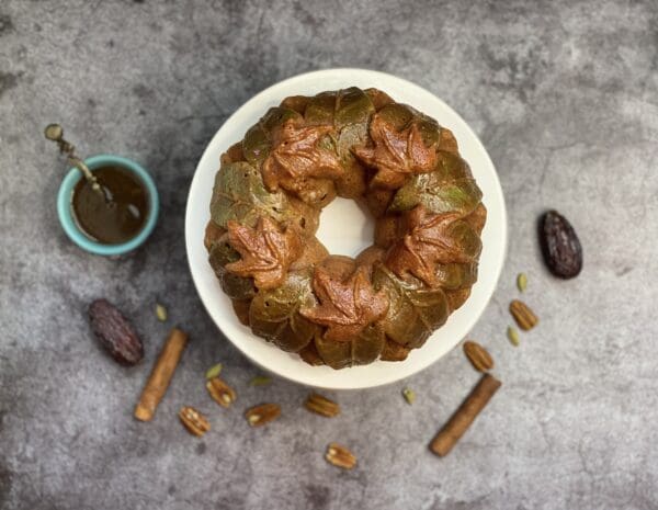 A chocolate bunt cake and pieces of chocolates, raisins, and peanuts on its background