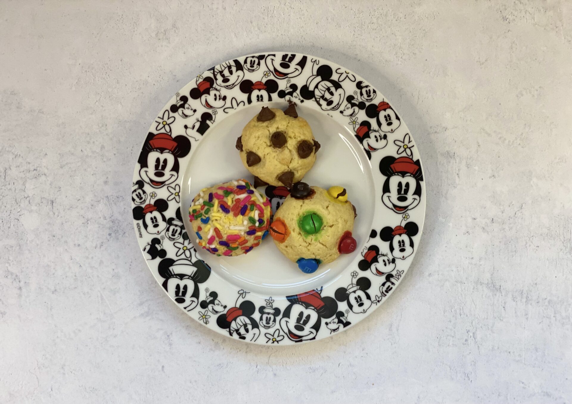 Three pieces of cookies with different toppings in a Minnie Mouse plate