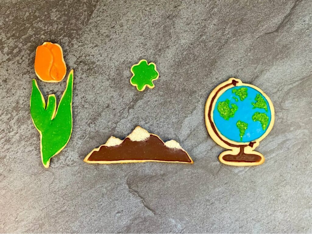Four cookies in different shapes, such as tulip, mountains, globe, and clover