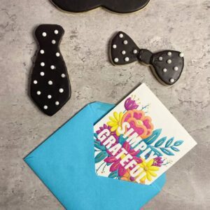 Three cupcakes in different designs, such as mustache, tie, and bow tie, and a card