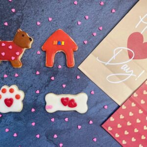 Four pieces of cookies in different shapes, such as dog, paw, bone, and dog house.