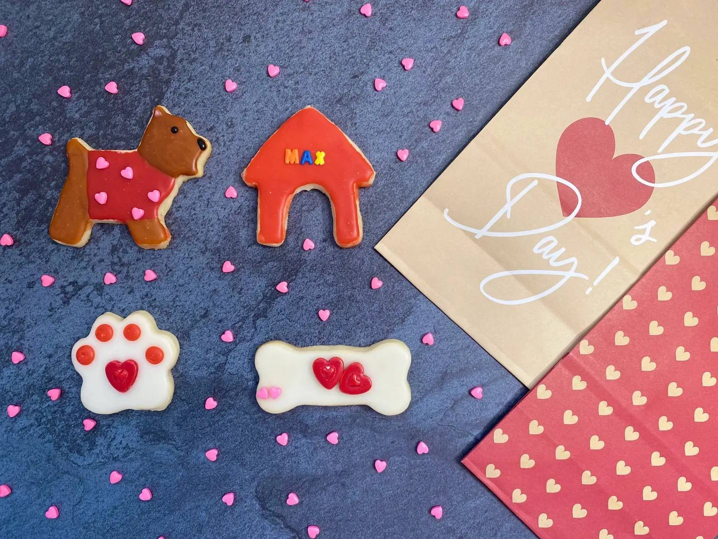 Four pieces of cookies in different shapes, such as dog, paw, bone, and dog house.