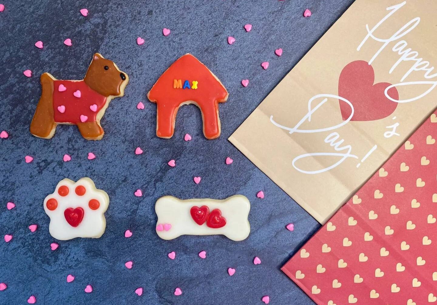 Four pieces of cookies in different shapes, such as dog, paw, bone, and dog house.